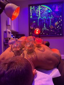 Rami Hamed, MMA fighter, receiving cupping therapy on his upper back under red infrared heat lamps at Acupuncture Zen in Delray Beach.