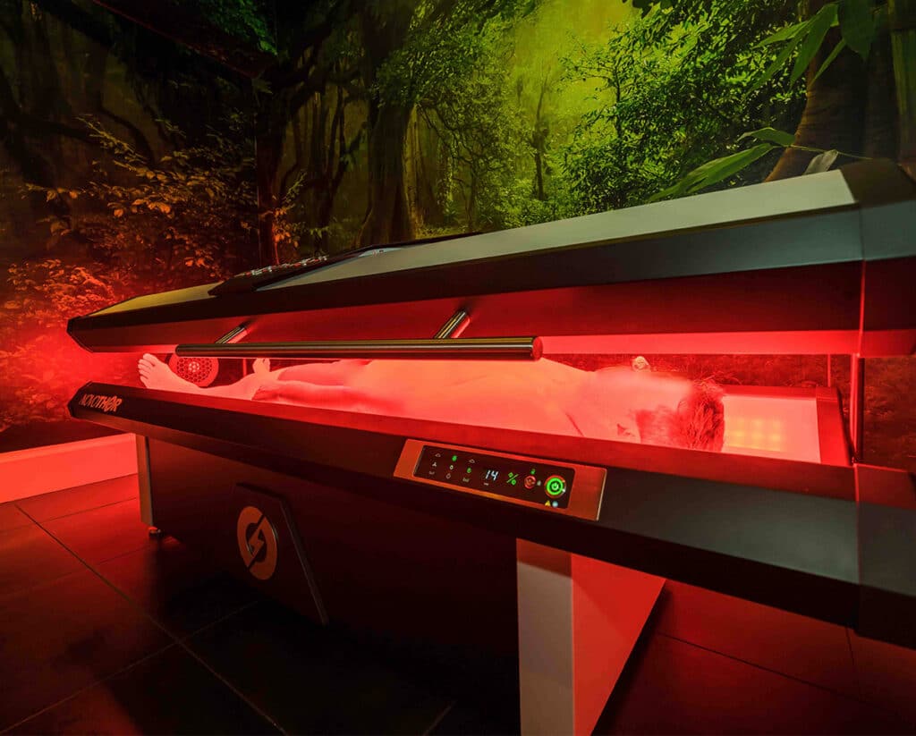 Patient inside the NovoTHOR whole-body red light therapy pod at Acupuncture Zen in Delray Beach
