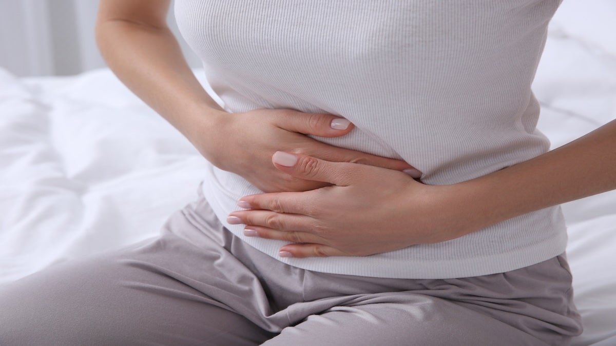 Woman holding her lower abdomen in discomfort, representing constipation