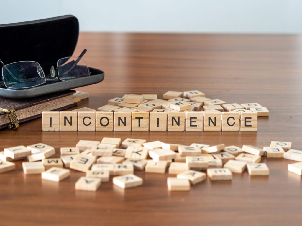 Letter tiles spelling the word incontinence beside a pair of glasses