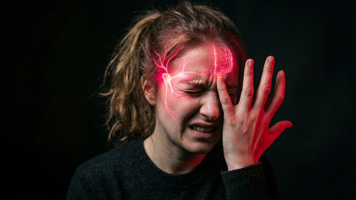 Woman gripping her head in pain with red nerve pathways glowing across her temple, migraine acupuncture in Delray Beach