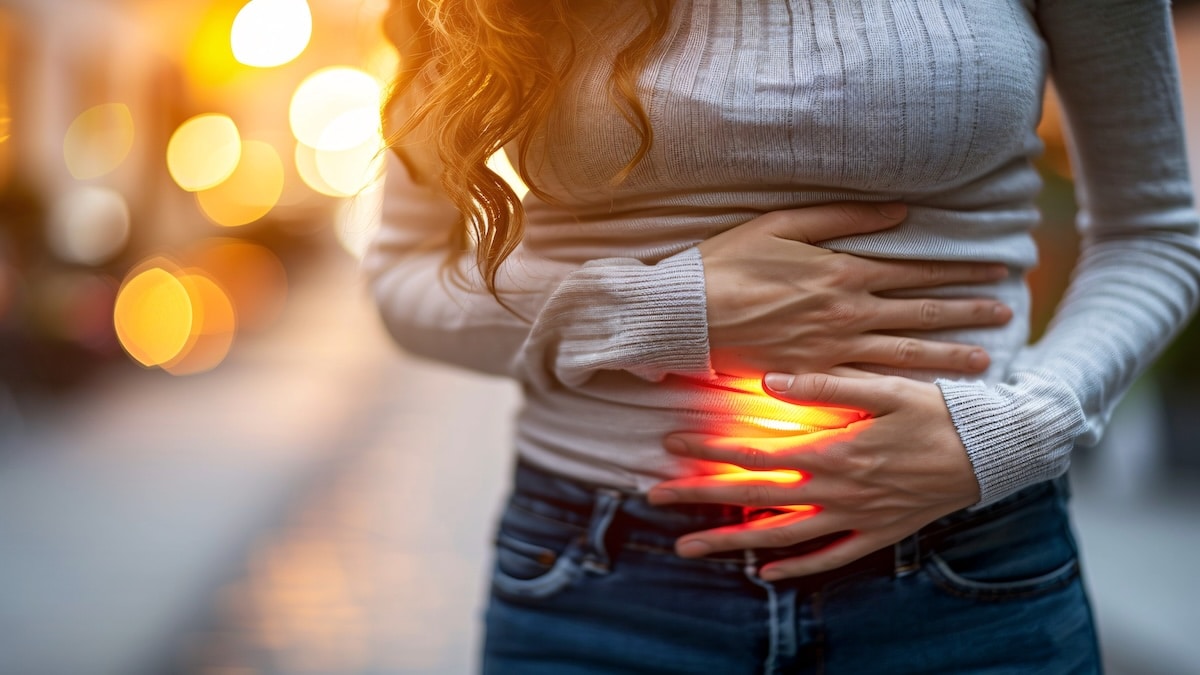 Woman holding her lower abdomen with the area glowing red and orange to show digestive pain, ulcerative colitis acupuncture in Delray Beach