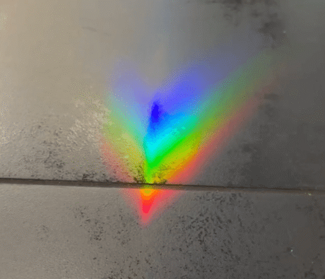 White light dispersed into a rainbow spectrum on a dark surface — frequency and wavelength made visible.